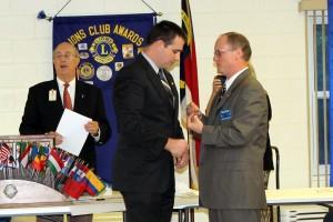 Lion Chris Norcross receives the Lion President pin from outgoing Lion President John Lynde