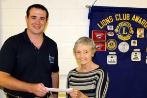 Lion Chris Norcross presents Jan Carlton with $1000 check for Western Wake Crisis Ministry